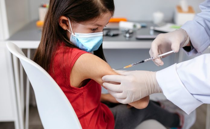 girl receiving coronavirus vaccine at doctor's office